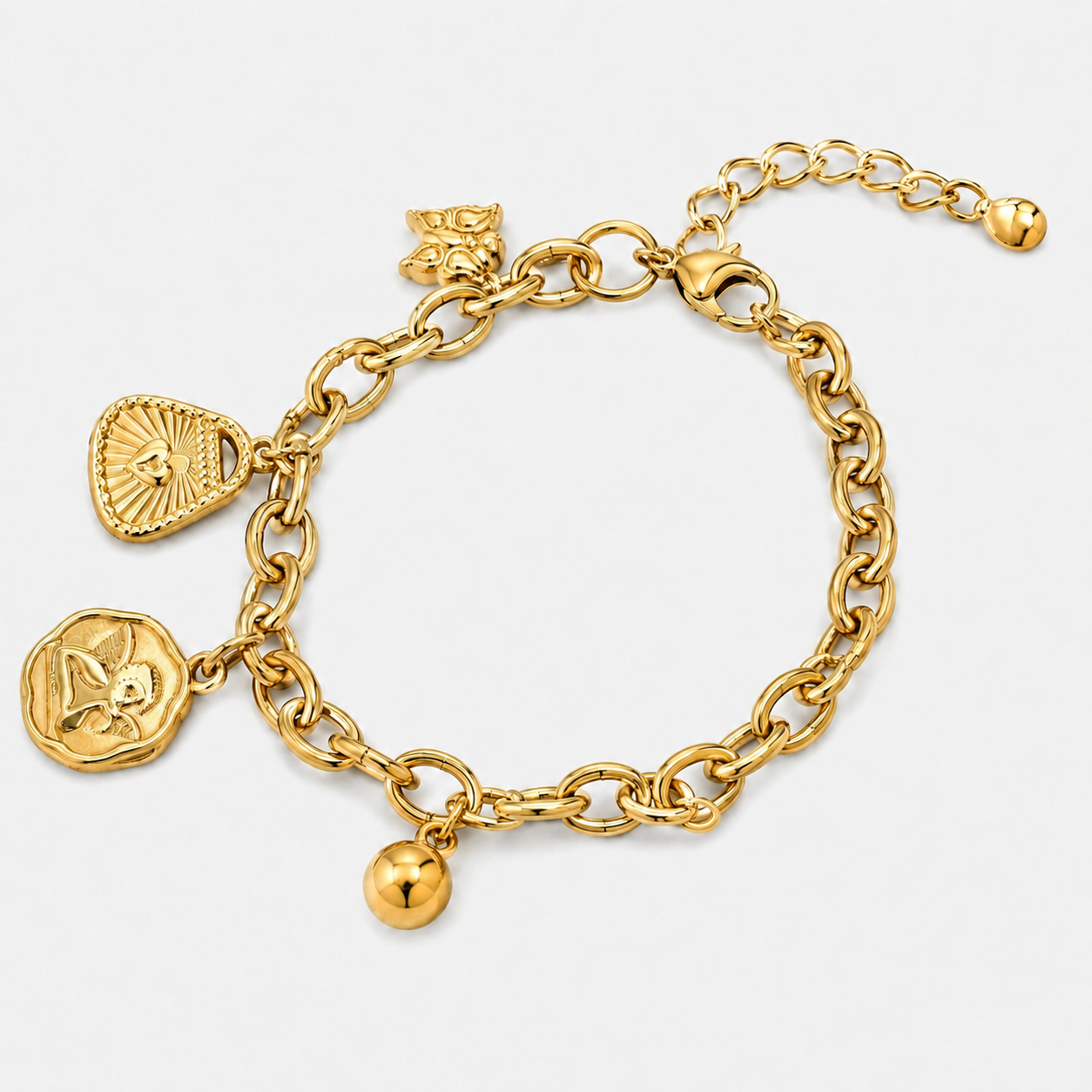 A gold chain bracelet with multiple charms, including a heart-shaped sunburst pendant, a round coin charm, a small ball charm, and a butterfly charm, displayed on a light gray background.