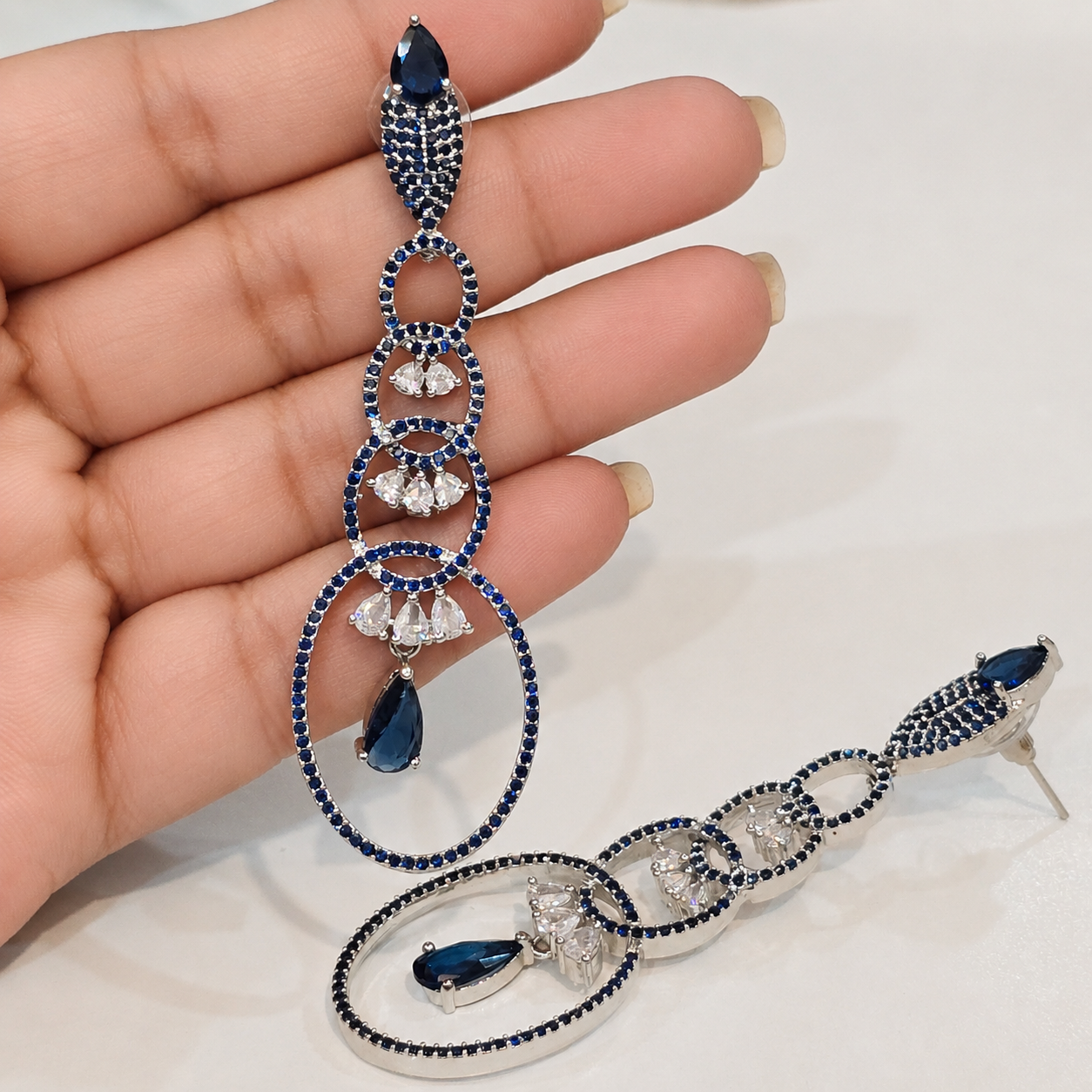 Elegant silver and blue gemstone necklace held by a hand on a light background