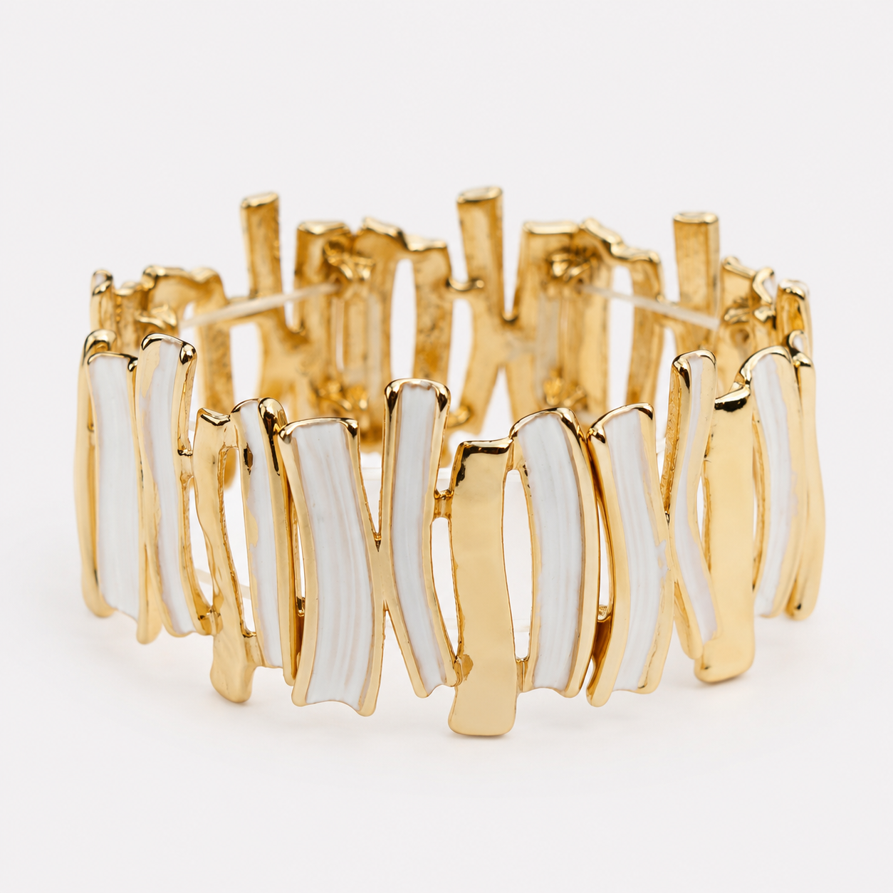 A gold-plated wavy cuff bracelet with white enamel inlay, shown on a clean white background.